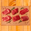 flatlay of six cut slices of steak on parchment paper