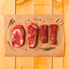 flatlay of four cut slices of steak on parchment paper